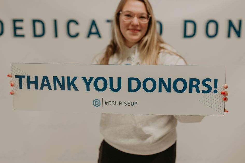 girl holding sign reading thank you donors